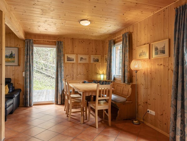 Un interior de madera con una mesa de comedor, sillas, un banco, un sofá y una lámpara de pie.