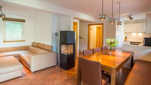 Un espacio habitable moderno con sofá, mesa de comedor, sillas, chimenea y zona de cocina.