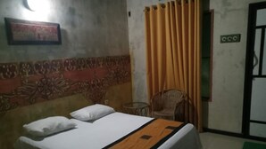 A bed with a patterned headboard, a chair, and a curtain.