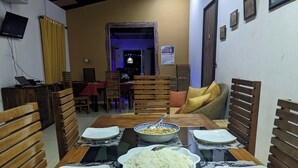 A dining area with a glass table set for four, surrounded by wooden chairs.