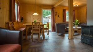 Interior acogedor de una cabaña con comedor, asientos y chimenea.
