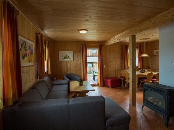 A cozy wooden interior with a sofa, a dining table, and a fireplace.