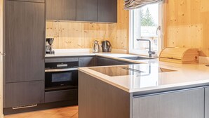 Una cocina moderna con armarios oscuros, un fregadero de acero inoxidable y un ventanal con cortina.
