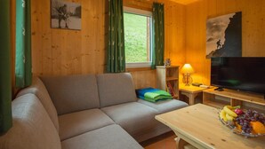A cozy cabin interior with a sofa, a TV, and a table with fruit.