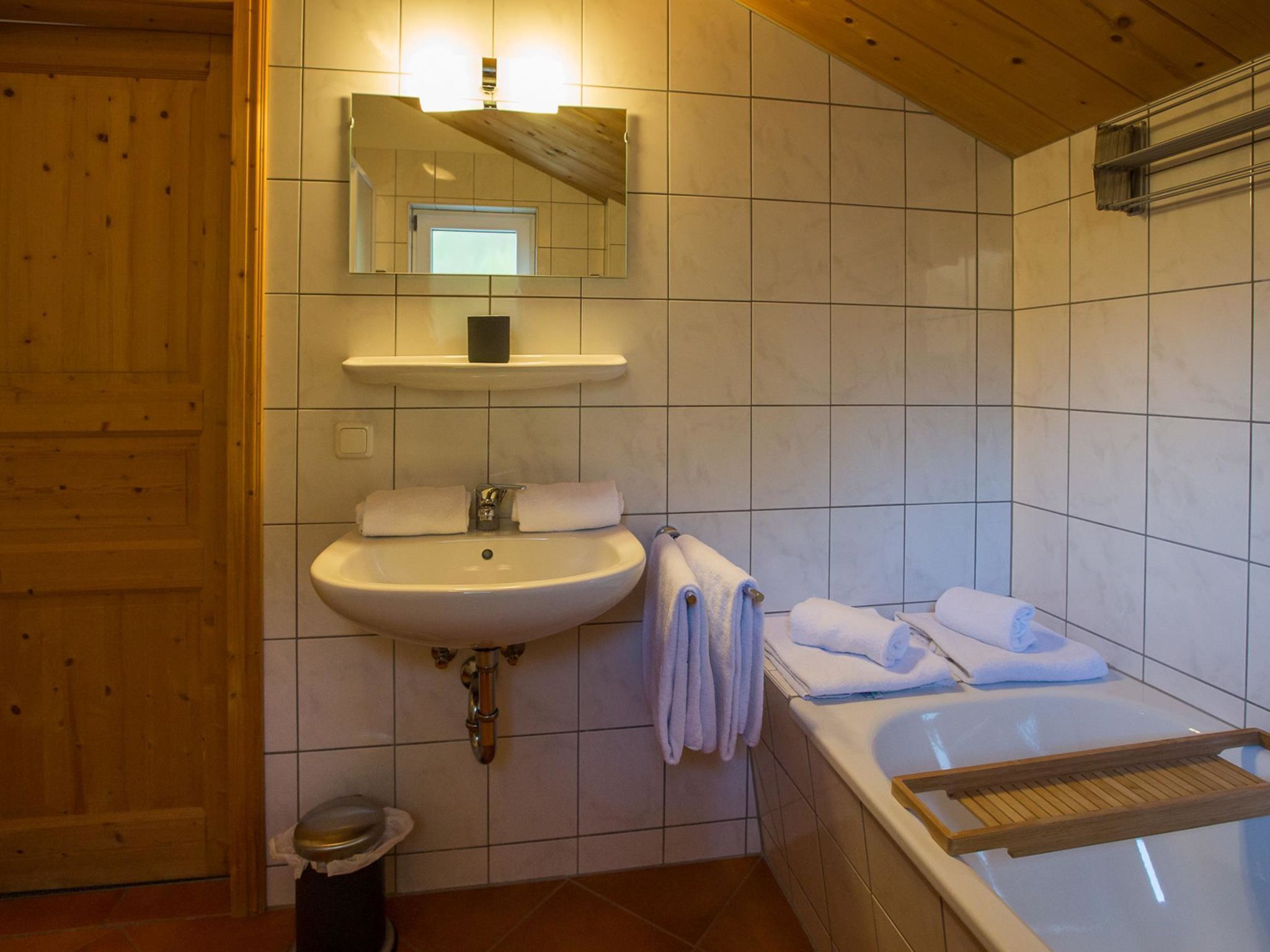 A bathroom with a sink, mirror, and bathtub.