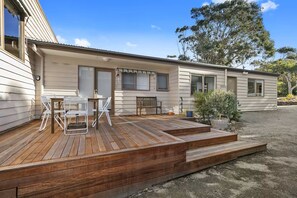 A single-story mobile home with a wooden deck and outdoor seating area.