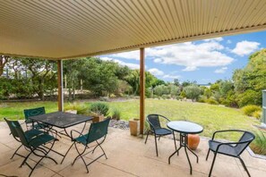 An outdoor patio with a covered area, a table, and chairs.