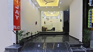 A hotel lobby with a marble floor, a reception desk, and a staircase leading to upper floors. - Hotel Vijaydeep Place Near Delhi Airport (New Delhi)