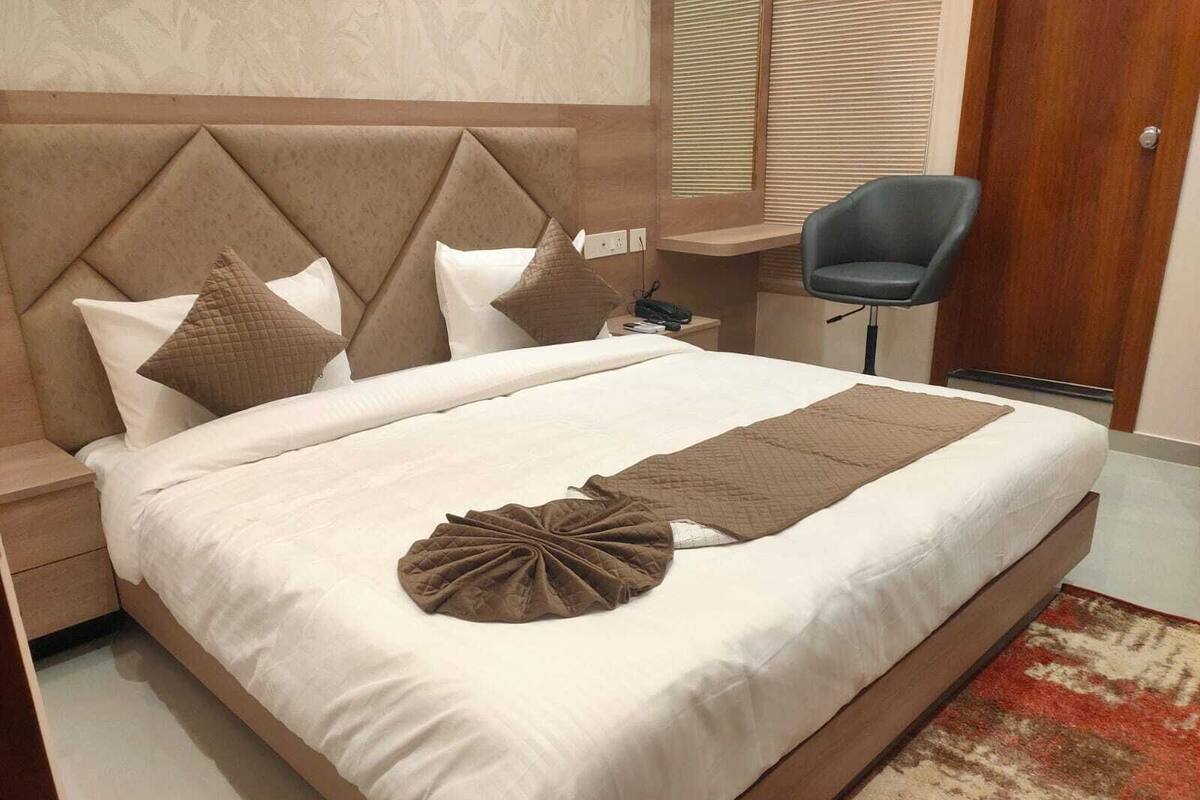 Una cama bien tendida con cabecera, almohadas y un objeto decorativo.