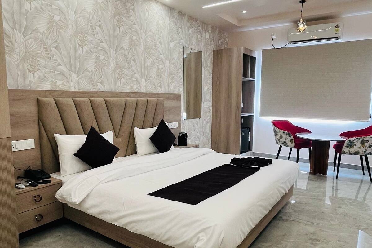 Una habitación de hotel moderna con una cama grande, un ventilador de techo, un escritorio con dos sillas y un ventanal amplio.