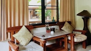 Un comedor de madera con una mesa y sillas, ventanas grandes con cortinas y una lámpara.