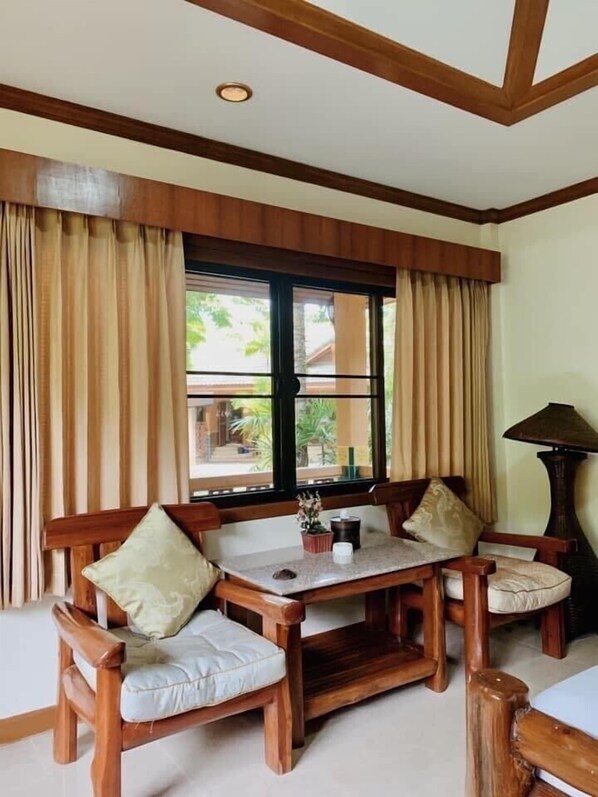 Un comedor de madera con una mesa y sillas, ventanas grandes con cortinas y una lámpara.
