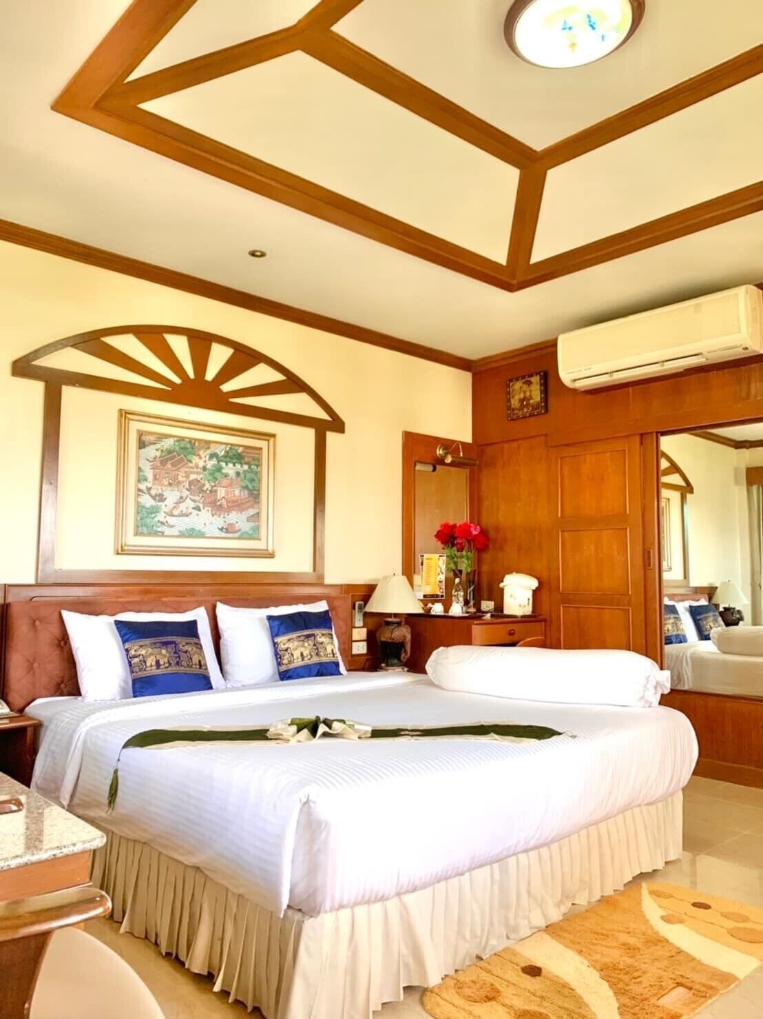 A hotel room with a large bed, wooden ceiling, and a framed picture on the wall.