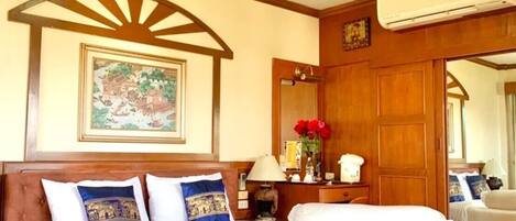 A hotel room with a large bed, wooden ceiling, and a framed picture on the wall.