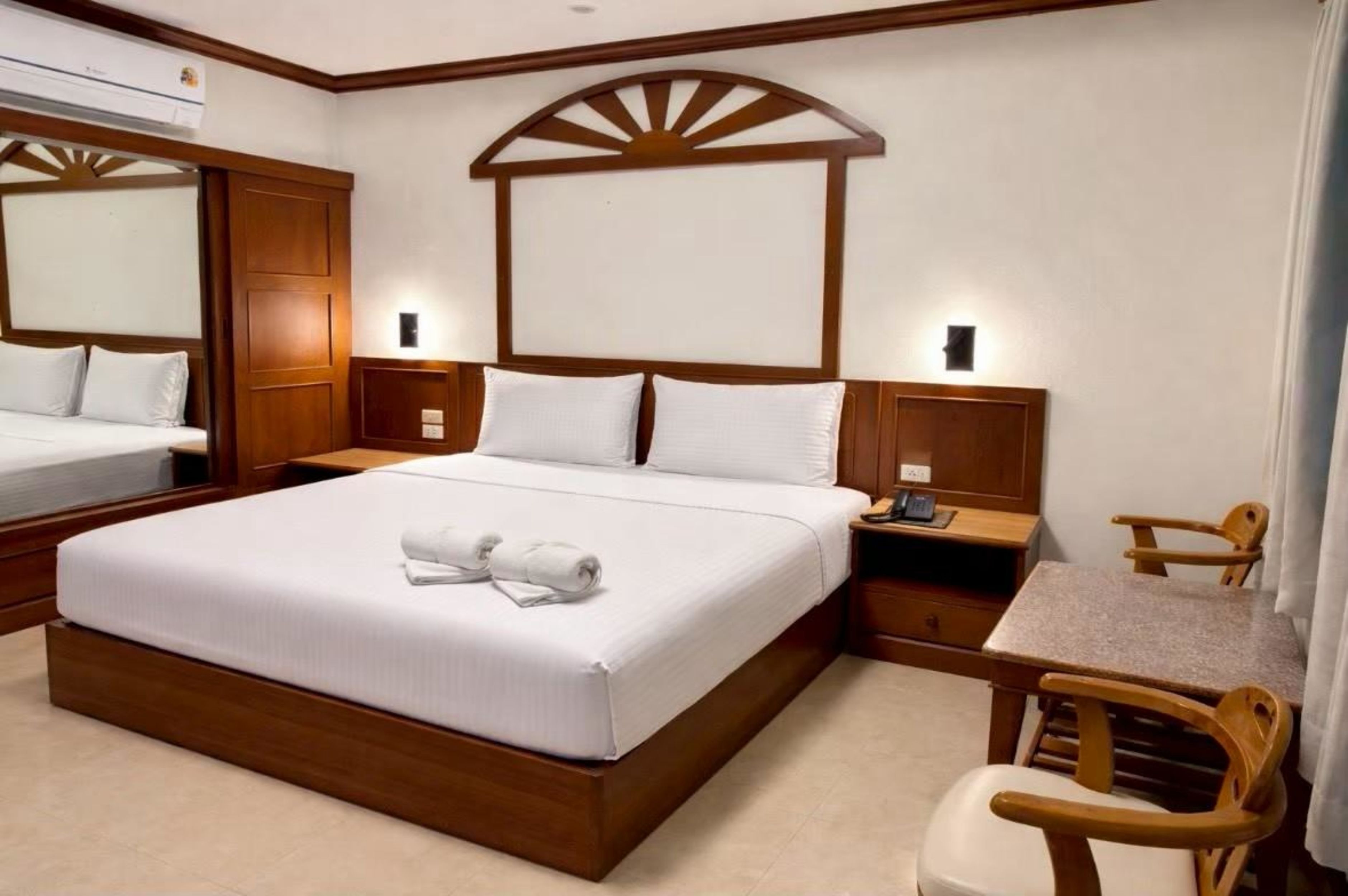 A hotel room with a large bed, a desk, and a chair.