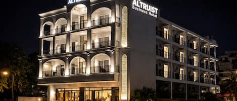 Un hotel de varios pisos con balcones y un letrero que dice 'The Altruist Business Hotel'.