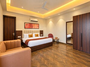 Habitación de hotel con cama, sofá, sillón, mesita, espejo y armario.