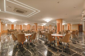 A spacious hotel dining area with marble flooring, round tables, and cushioned chairs. - The Altruist Gurugram Hotel (Gurugram)