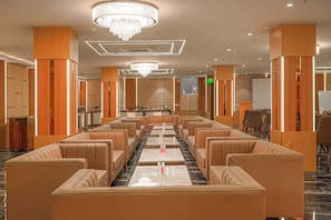 A hotel lobby with a long row of leather sofas, a central chandelier, and a reception desk. - The Altruist Gurugram Hotel (Gurugram)