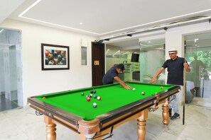 A pool table with balls, a framed picture on the wall, and a door with a warning sign.