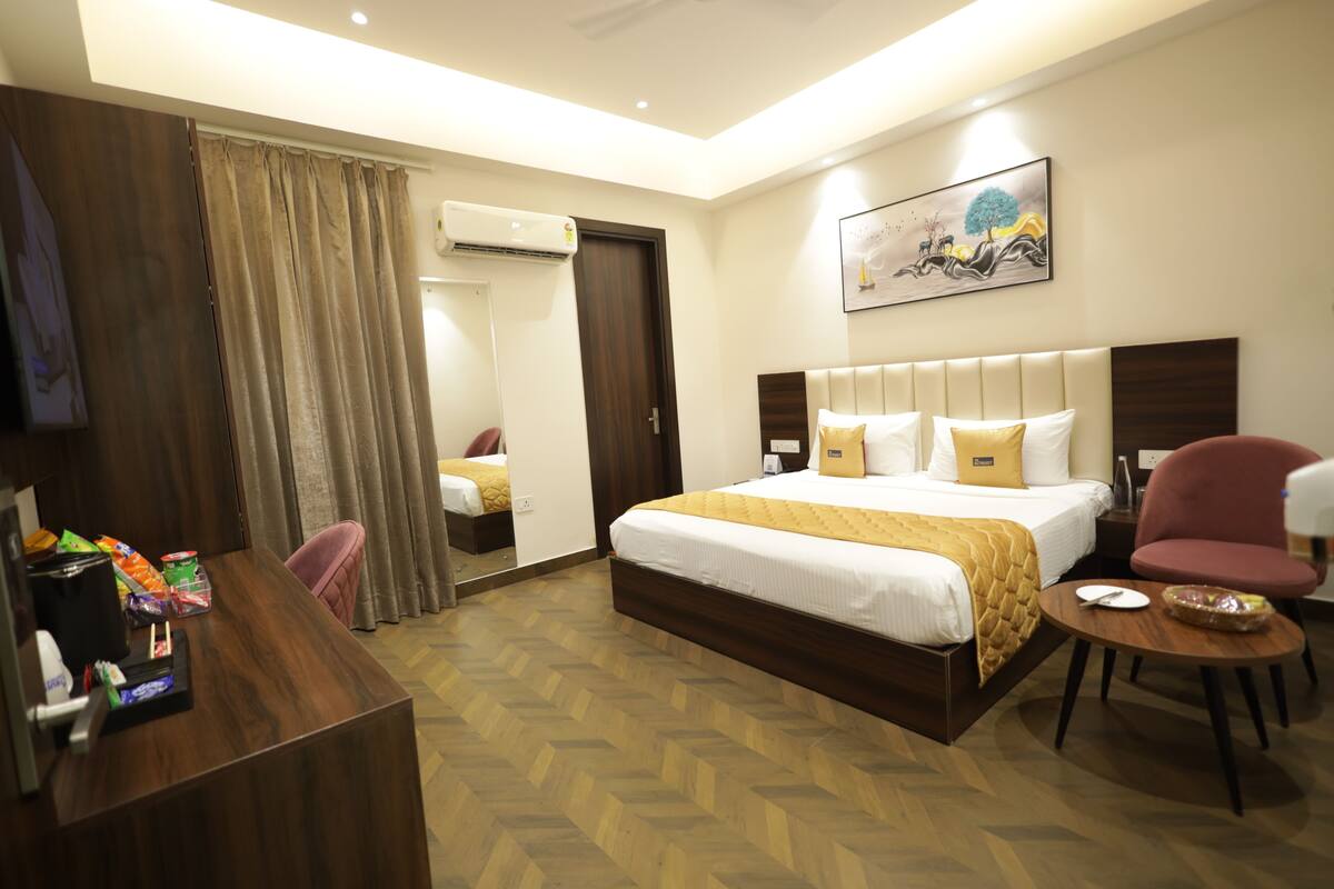 A hotel room with a bed, a desk, a chair, and a small table.