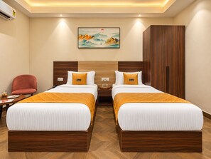 A hotel room with two beds, a wooden wardrobe, a red chair, a painting on the wall, and a wooden floor. - The Altruist Gurugram Hotel (Gurugram)