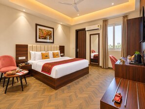 A hotel room with a bed, a desk, a chair, an air conditioning unit, and a television. - The Altruist Gurugram Hotel (Gurugram)