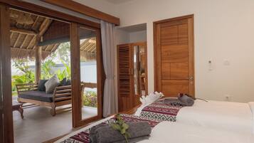 A hotel room with a large bed, a wooden bench, and a view of the outdoors.