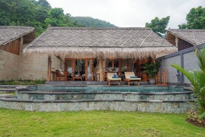 Un complexe hôtelier doté de villas aux toits de chaume, d’une piscine et d’un jardin luxuriant.