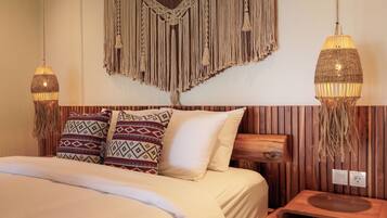 Un lit avec des coussins à motifs, une décoration murale en macramé et deux lampes suspendues.