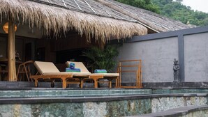Una estructura con techo de paja, sillones de descanso y una estatua.
