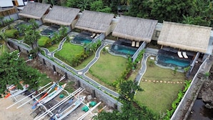 Un resort con varias cabañas sobre el agua, piscinas y un jardín bien cuidado.
