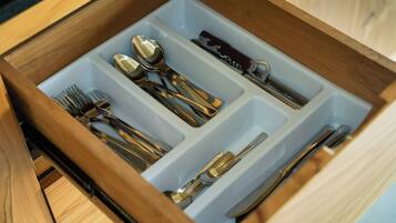 A drawer with compartments containing various utensils including forks, spoons, knives, and a pair of scissors.