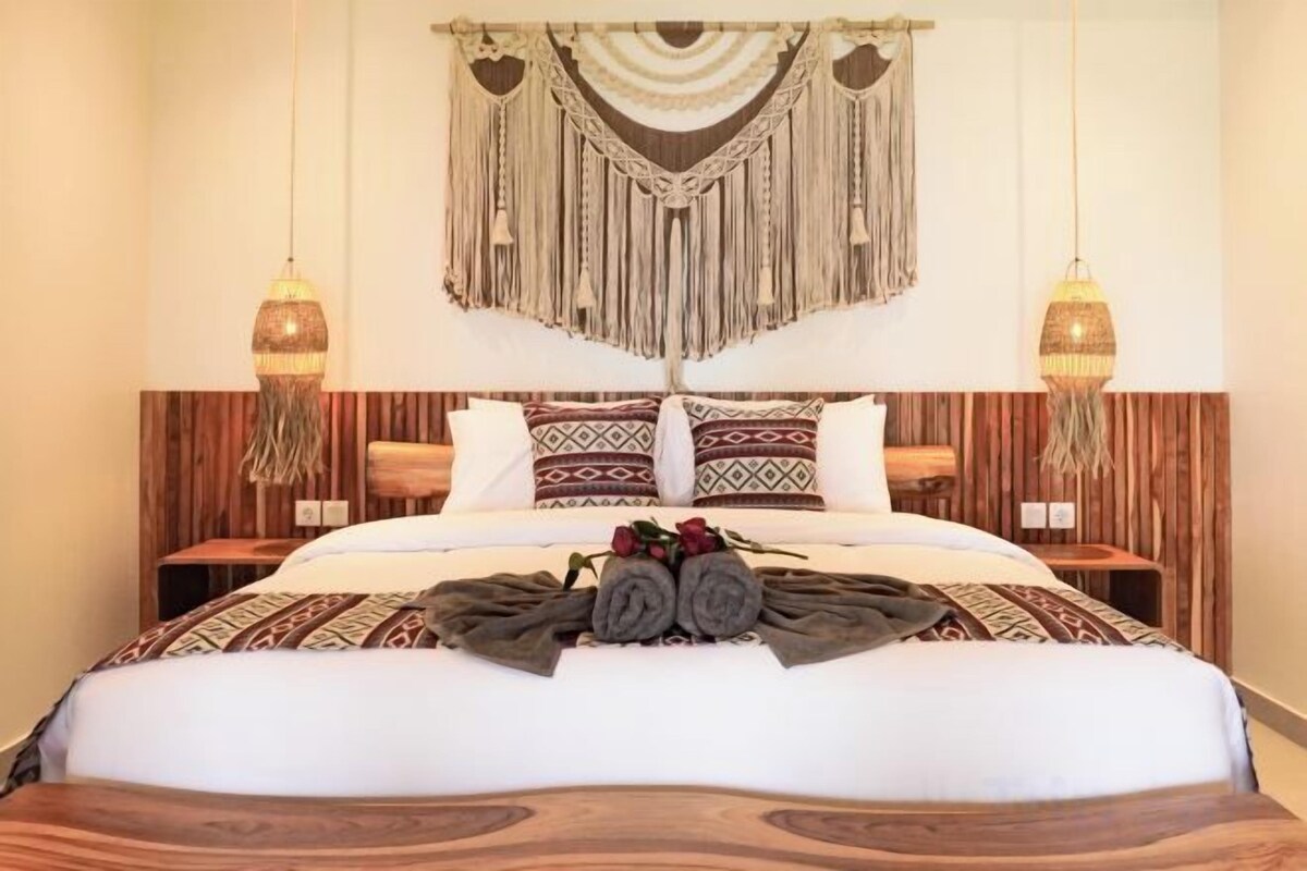 Una cama con cabecera de madera, dos mesitas de noche y un colgador decorativo de macramé.