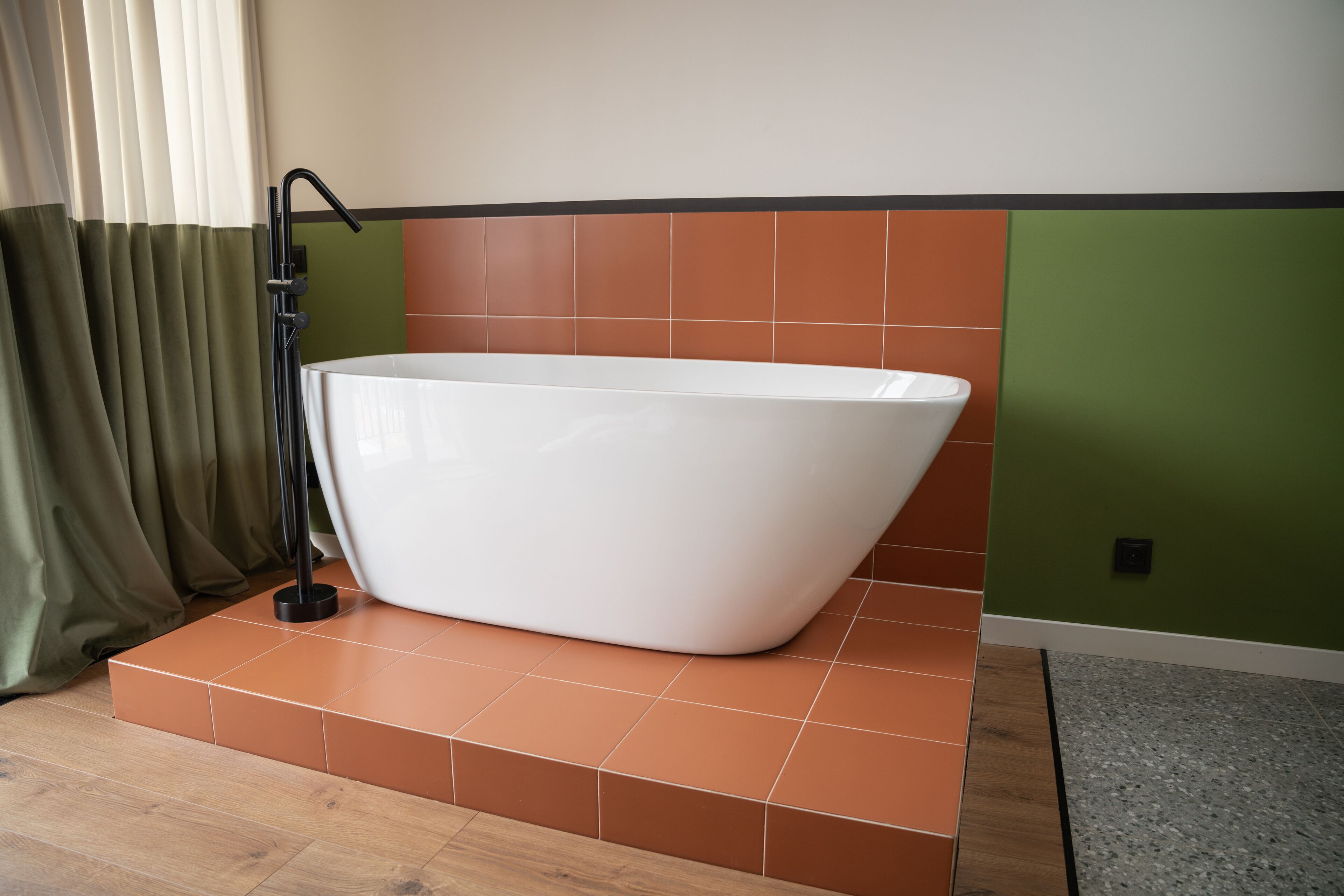 A modern bathroom with a freestanding bathtub, a showerhead, and a tiled floor.