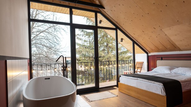 A modern bedroom with a large window, a bathtub, and a bed. - Major's House Hotel (Step'anavan)