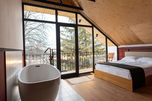 Un dormitorio moderno con un ventanal grande, una bañera y una cama.