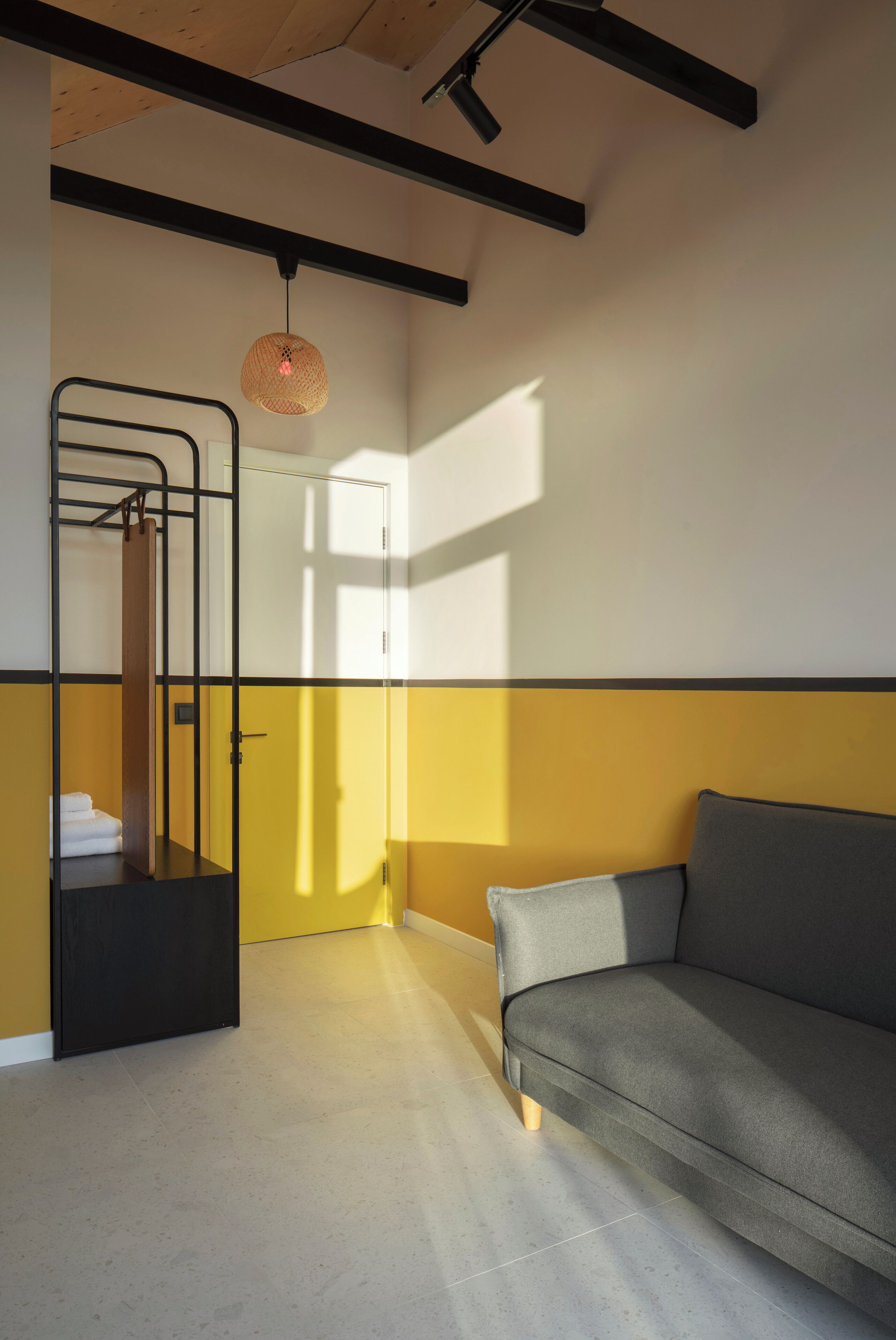 A room with a bunk bed, a sofa, and a hanging light fixture.