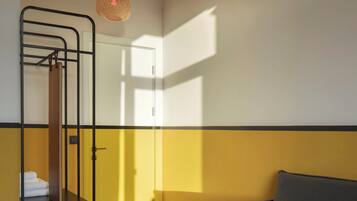 A room with a bunk bed, a sofa, and a hanging light fixture.