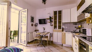 Een keuken met een eethoek, een televisie en een raam.