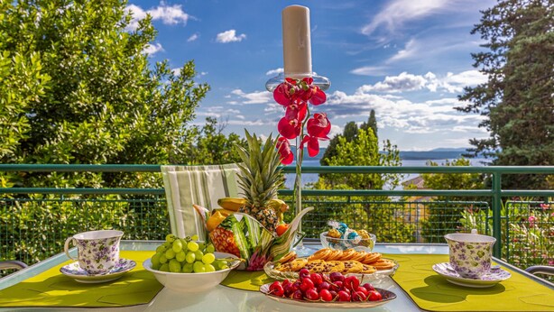 Een tafel gedekt met fruit, koekjes en een kaars, met uitzicht op een prachtig landschap.