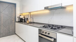 A modern kitchen with white cabinets, a marble backsplash, a gas stove, and a built-in oven.