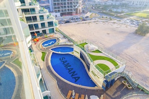 A rooftop swimming pool with the name 'SAMANA' and a modern building complex in the background. - Bloomfield Luxury Studio Samana Golf (Dubai)