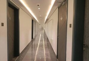 A long, narrow hotel corridor with doors on both sides, numbered signs, and a tiled floor. - Bloomfield Luxury Studio Samana Golf (Dubai)