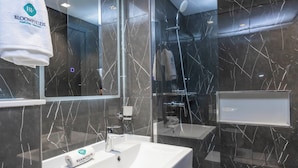 A modern bathroom with a white sink, a towel hanging on the wall, and a glass shower enclosure.