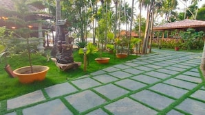 A garden with a stone pathway, potted plants, and a small rock structure.