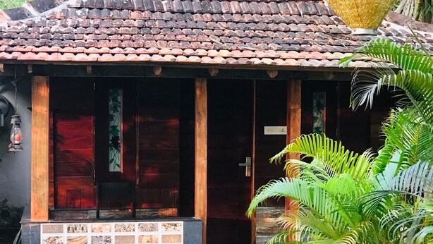 A small, traditional house with a tiled roof and a wooden porch.