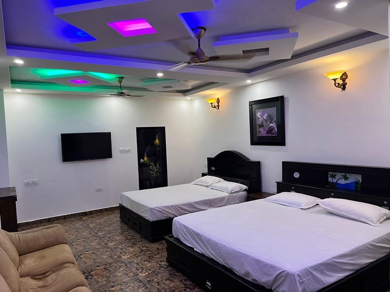 A hotel room with two beds, a TV, a ceiling fan, and a painting on the wall.