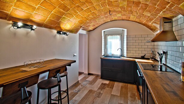 A kitchen with a brick ceiling, wooden flooring, a central island, and a window. - Club Villamar - Kaixo is a detached Spanish villa with a private pool, garden, BBQ, spacious livi... (Calonge)