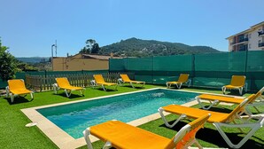 A rooftop pool area with yellow lounge chairs and a view of a hillside. - Club Villamar - Kaixo is a detached Spanish villa with a private pool, garden, BBQ, spacious livi... (Calonge)